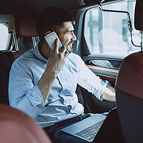 Handsome business man working on a computer in car